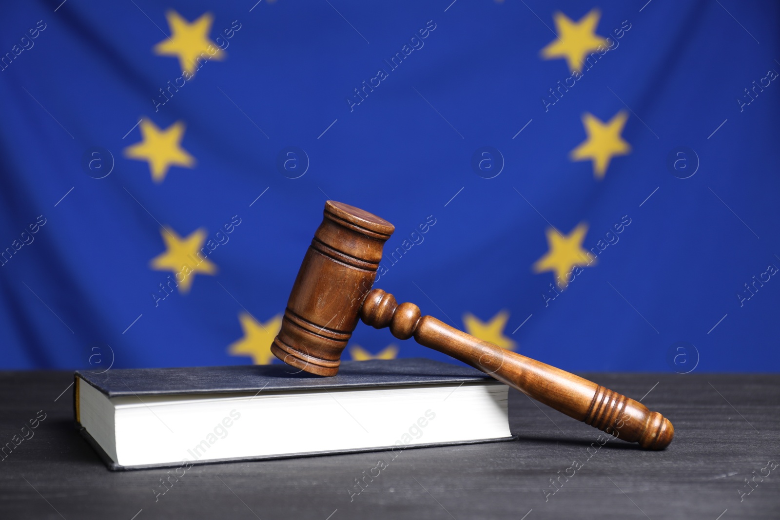 Photo of Judge's gavel and book on grey table against European Union flag