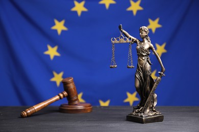 Figure of Lady Justice and judge's gavel on grey table against European Union flag