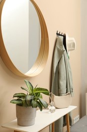 Coat rack with clothes, mirror and storage bench in hallway. Interior design