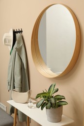 Photo of Coat rack with clothes, mirror and storage bench in hallway. Interior design