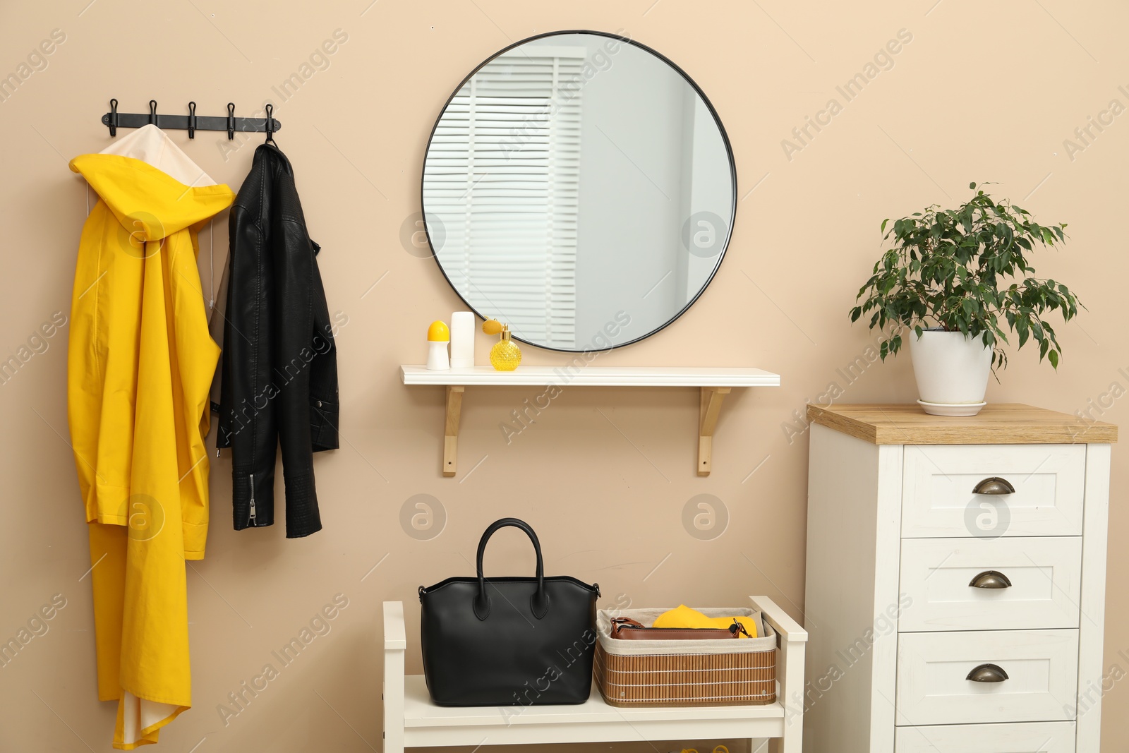 Photo of Coat rack with clothes, mirror, shoe storage bench and chest of drawers in hallway. Interior design