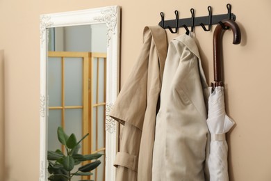 Photo of Coat rack with clothes and mirror in hallway. Interior design