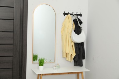 Mirror, rack with clothes and shoe storage bench in hallway. Interior design