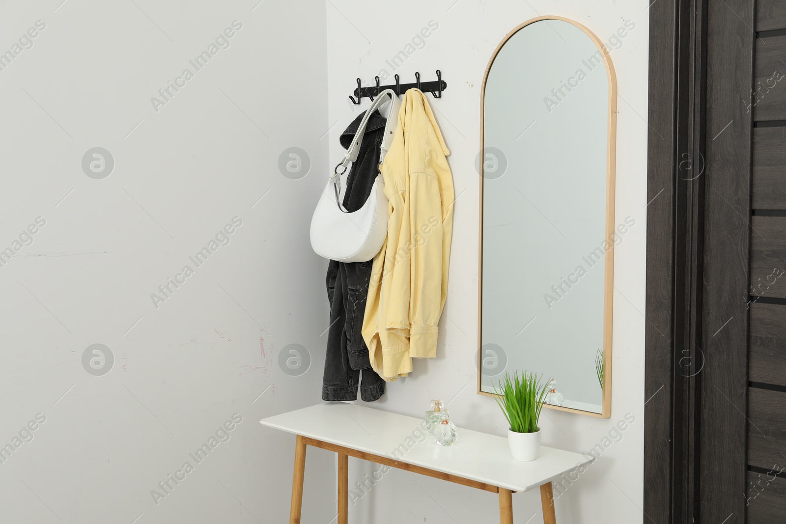 Photo of Mirror, rack with clothes and shoe storage bench in hallway. Interior design