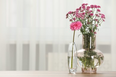 Beautiful pink flowers in vases on table at home, space for text