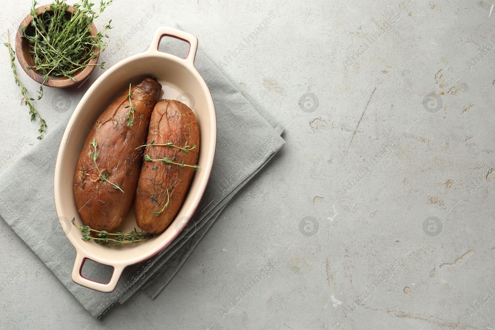 Tasty cooked sweet potatoes served with thyme on light grey table, flat lay. Space for text Photo of Tasty cooked sweet potatoes served with thyme on light grey table, flat lay. Space for text