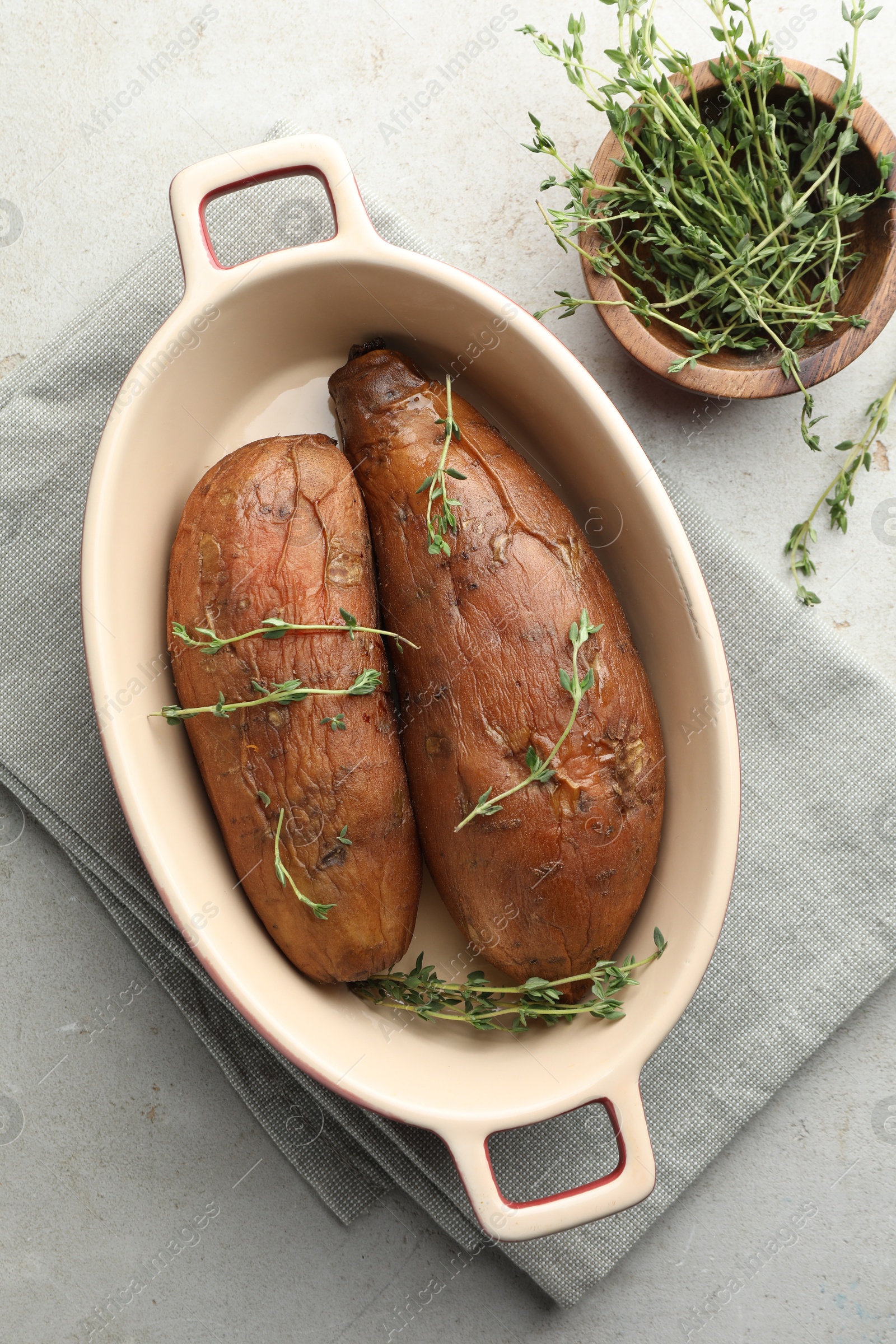 Tasty cooked sweet potatoes served with thyme on light grey table, flat lay Photo of Tasty cooked sweet potatoes served with thyme on light grey table, flat lay