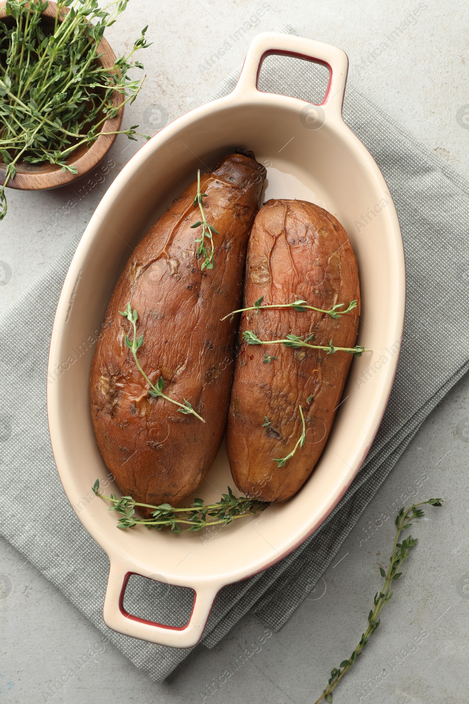 Photo of Tasty cooked sweet potatoes served with thyme on light grey table, flat lay