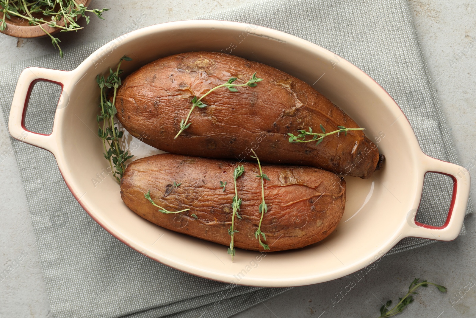 Tasty cooked sweet potatoes served with thyme on light grey table, flat lay Photo of Tasty cooked sweet potatoes served with thyme on light grey table, flat lay