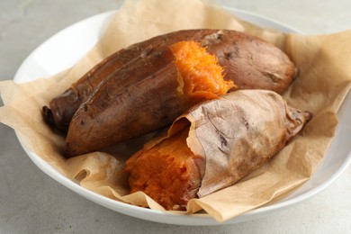 Photo of Tasty cooked sweet potatoes served on light grey table, closeup