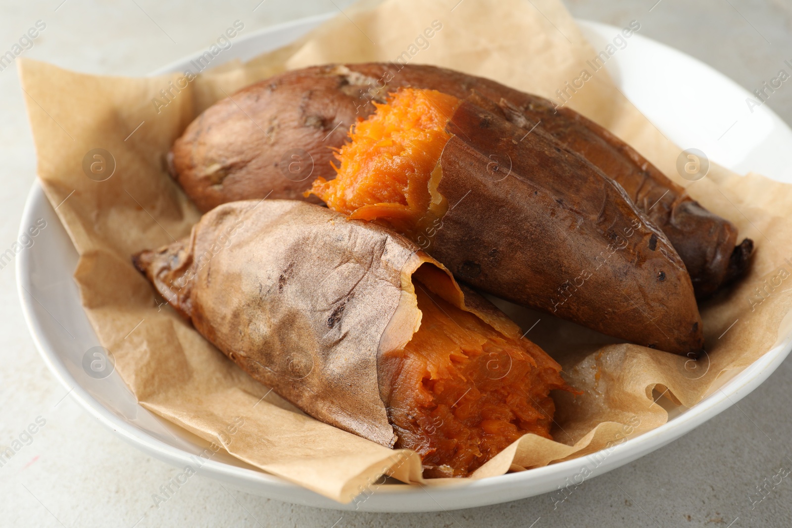 Photo of Tasty cooked sweet potatoes served on light grey table, closeup