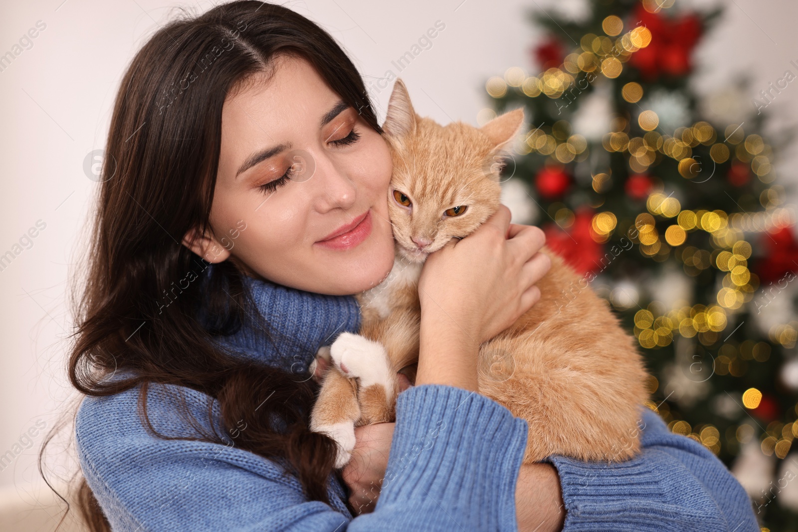 Photo of Woman with cute ginger cat in room decorated for Christmas