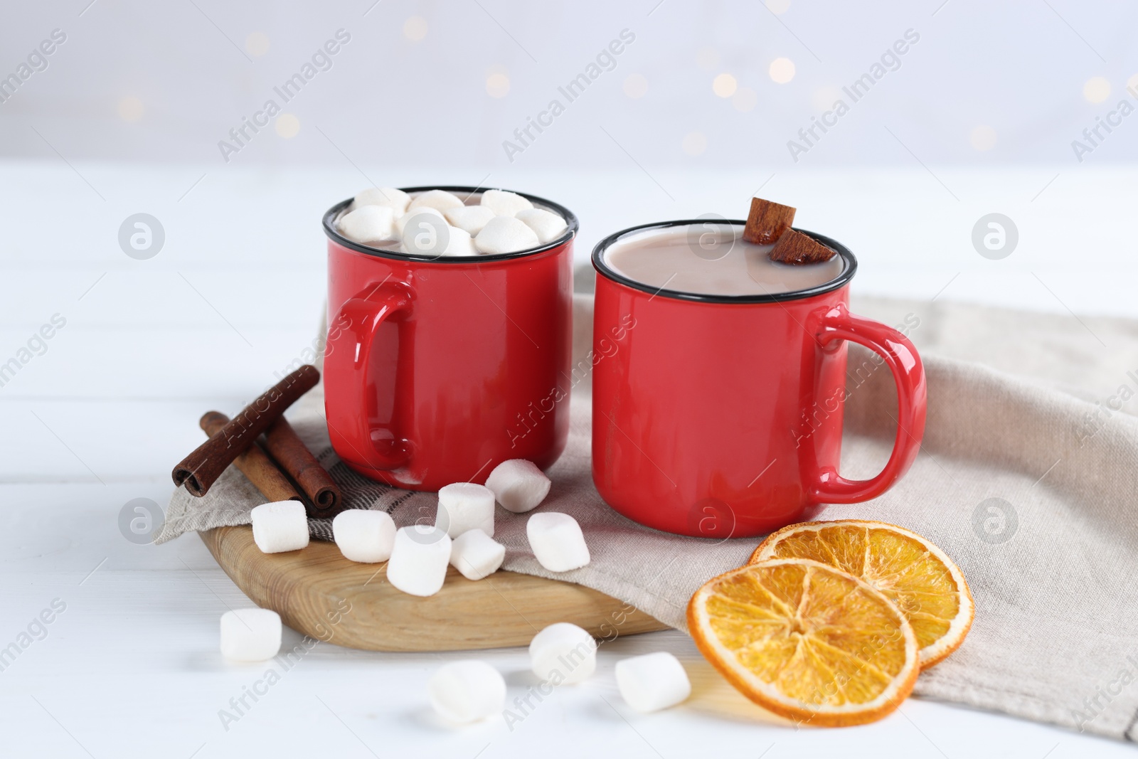 Photo of Yummy cocoa with marshmallows, dried orange slices and spices on white wooden table