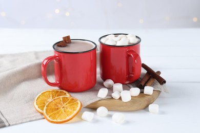 Photo of Yummy cocoa with marshmallows, dried orange slices and spices on white wooden table