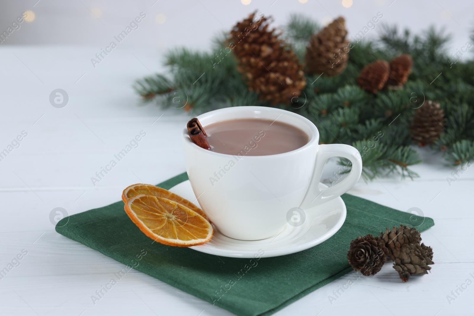 Photo of Yummy cocoa in cup and fir tree branches on white wooden table