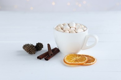 Photo of Yummy cocoa with marshmallows in cup, dried orange slices and spices on white wooden table