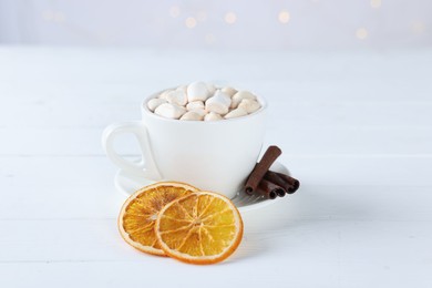 Photo of Yummy cocoa with marshmallows in cup, dried orange slices and spices on white wooden table