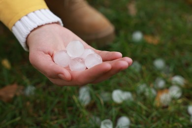 Photo of Woman holding hail grains after thunderstorm outdoors, closeup