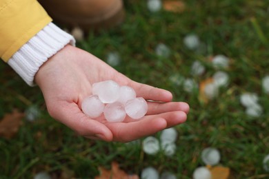 Photo of Woman holding hail grains after thunderstorm outdoors, closeup