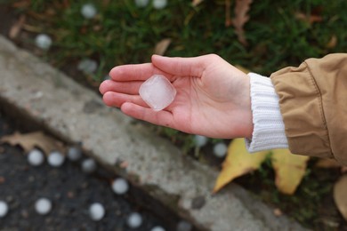 Woman holding hail grain after thunderstorm outdoors, closeup