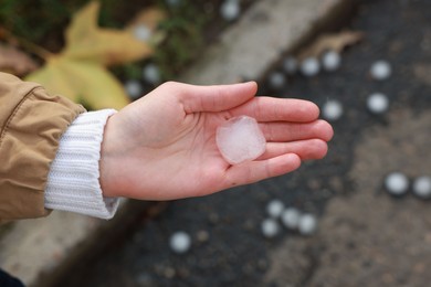 Photo of Woman holding hail grain after thunderstorm outdoors, closeup