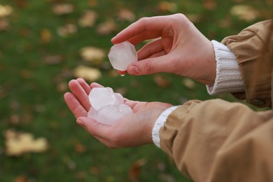 Photo of Woman holding hail grains after thunderstorm outdoors, closeup