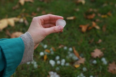 Woman holding hail grain after thunderstorm outdoors, closeup