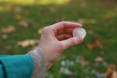 Photo of Woman holding hail grain after thunderstorm outdoors, closeup