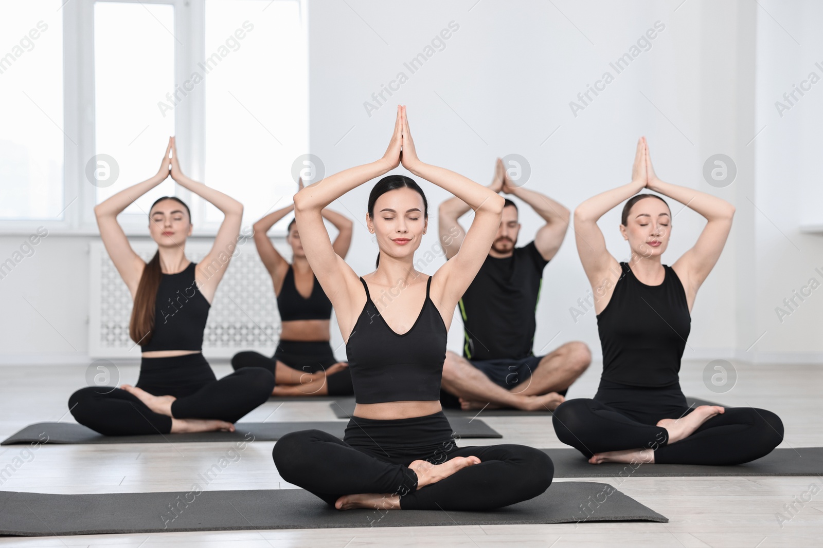 Photo of Group of people meditating on mats in yoga class