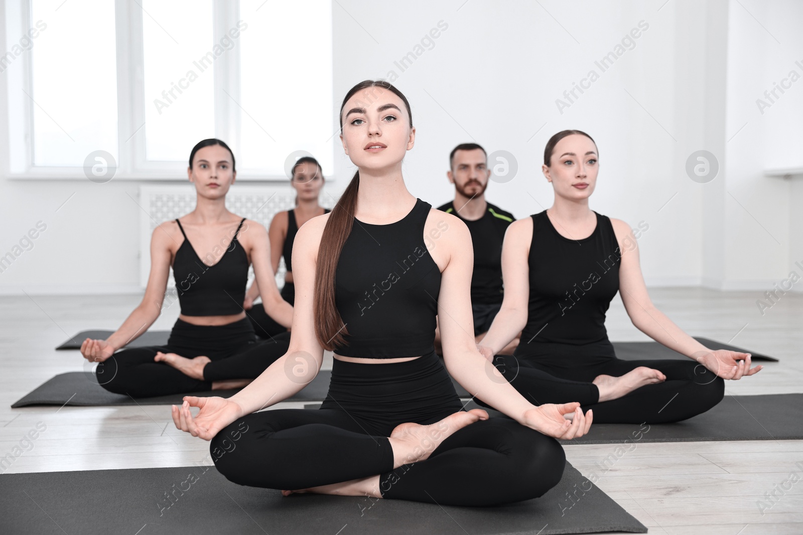 Photo of Group of people meditating on mats in yoga class