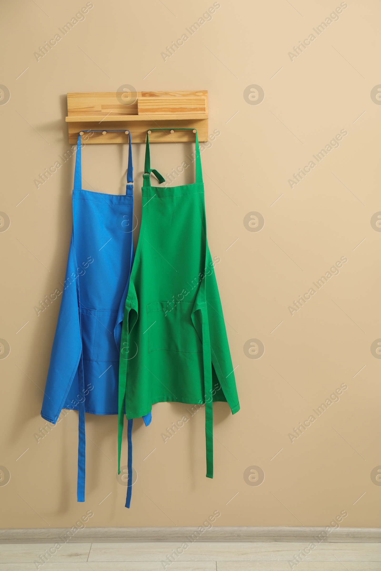 Photo of Two chef's aprons hanging on beige wall