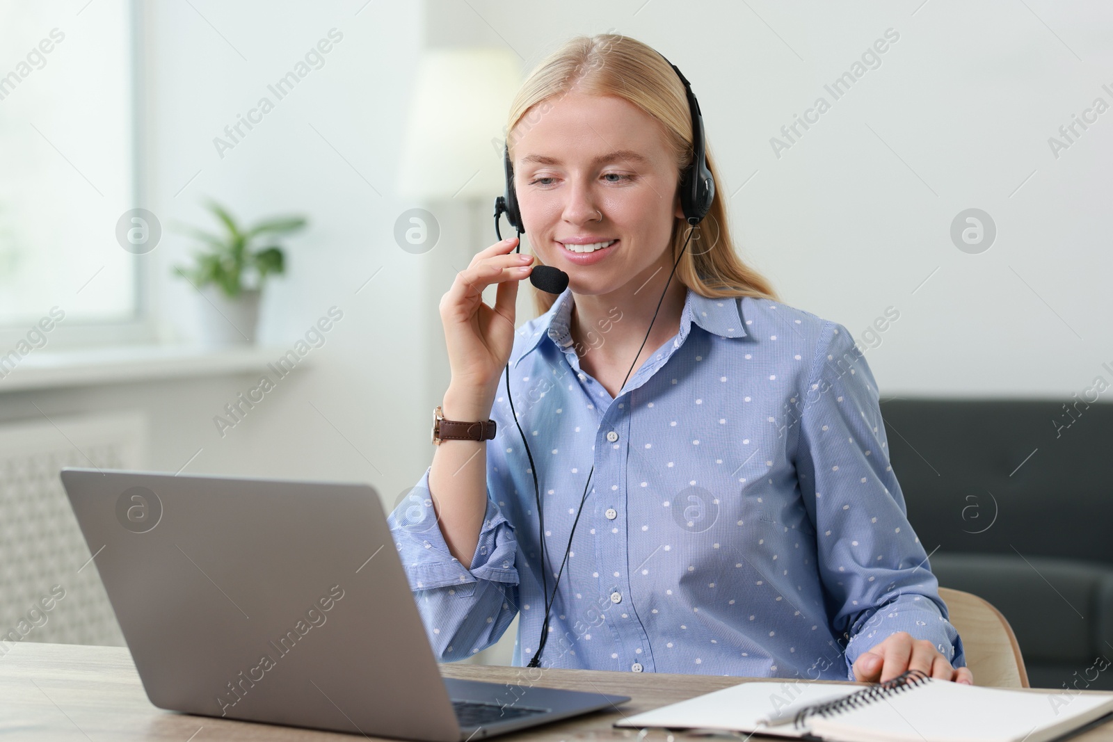 Photo of Interpreter in headset working with laptop at table indoors