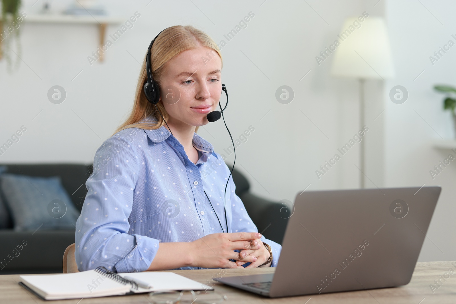 Photo of Interpreter in headset working with laptop at table indoors