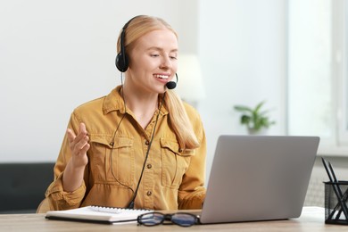 Interpreter in headset having video chat via laptop at table indoors