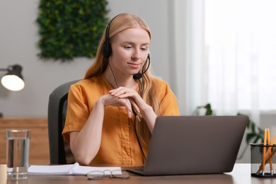 Interpreter in headset working with laptop at table indoors