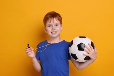 Photo of Little boy with whistle and soccer ball on orange background