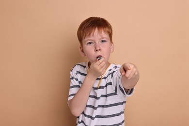 Little boy blowing whistle on beige background