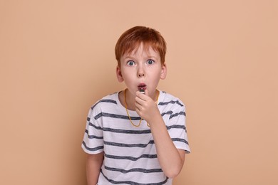 Little boy blowing whistle on beige background