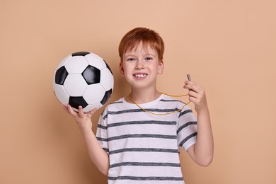 Photo of Little boy with soccer ball and whistle on beige background