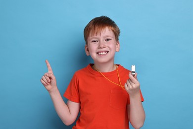 Photo of Little boy with whistle on light blue background