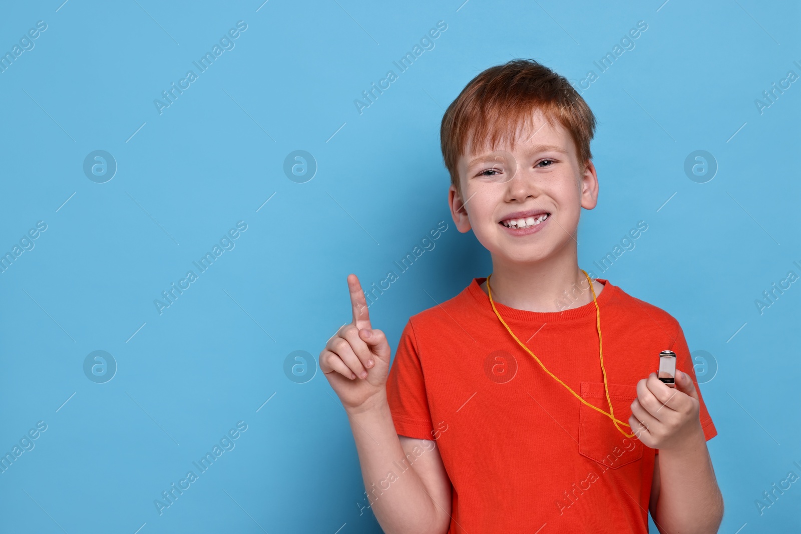 Photo of Little boy with whistle on light blue background, space for text