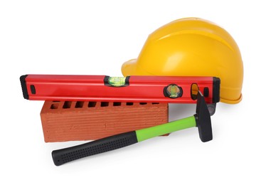 Photo of Yellow hard hat, building level, hammer and red brick isolated on white. Construction tools