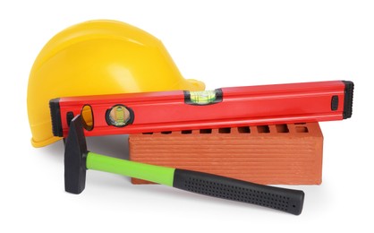 Photo of Yellow hard hat, building level, hammer and red brick isolated on white. Construction tools