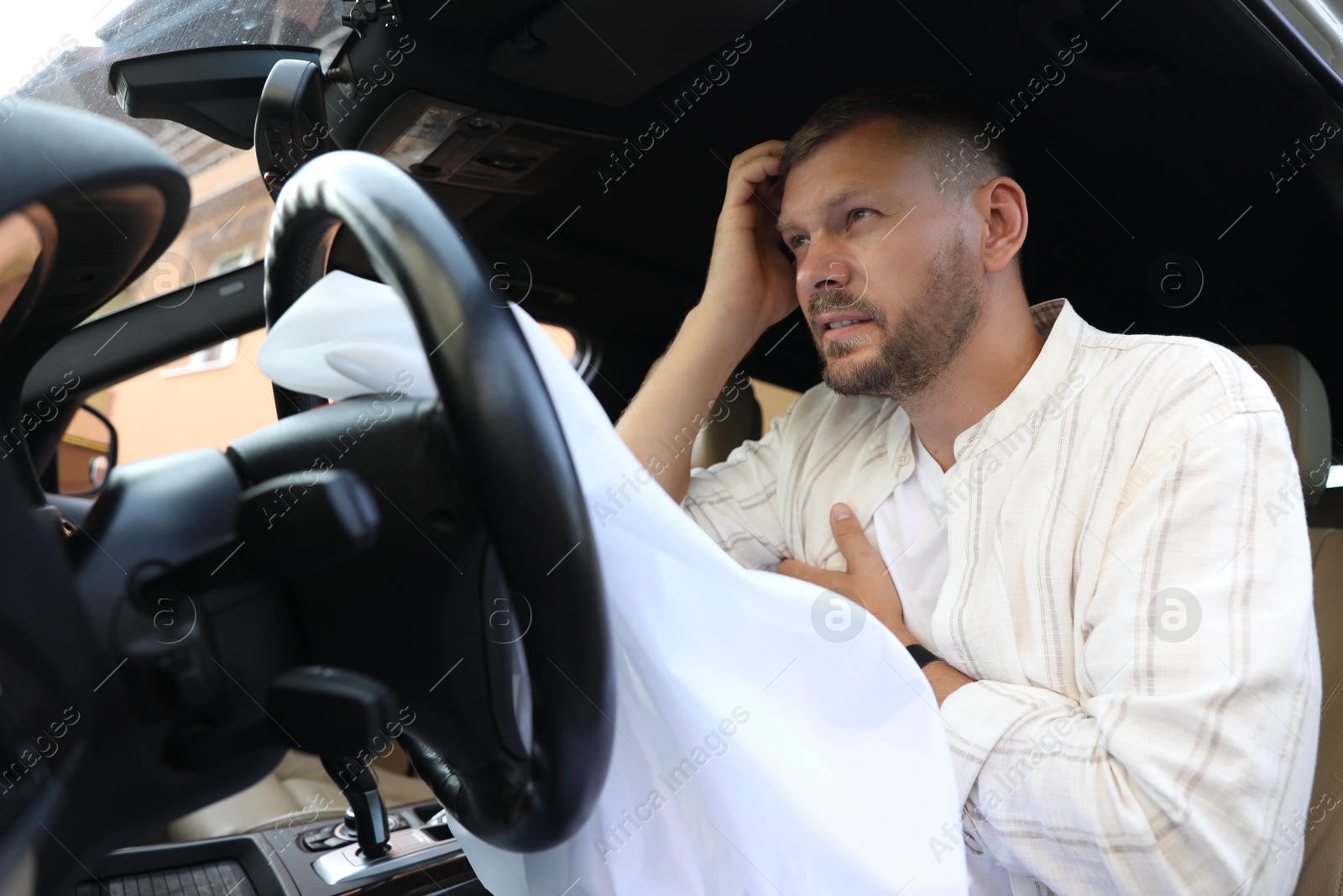 Photo of Injured man near opened airbag in automobile after car accident