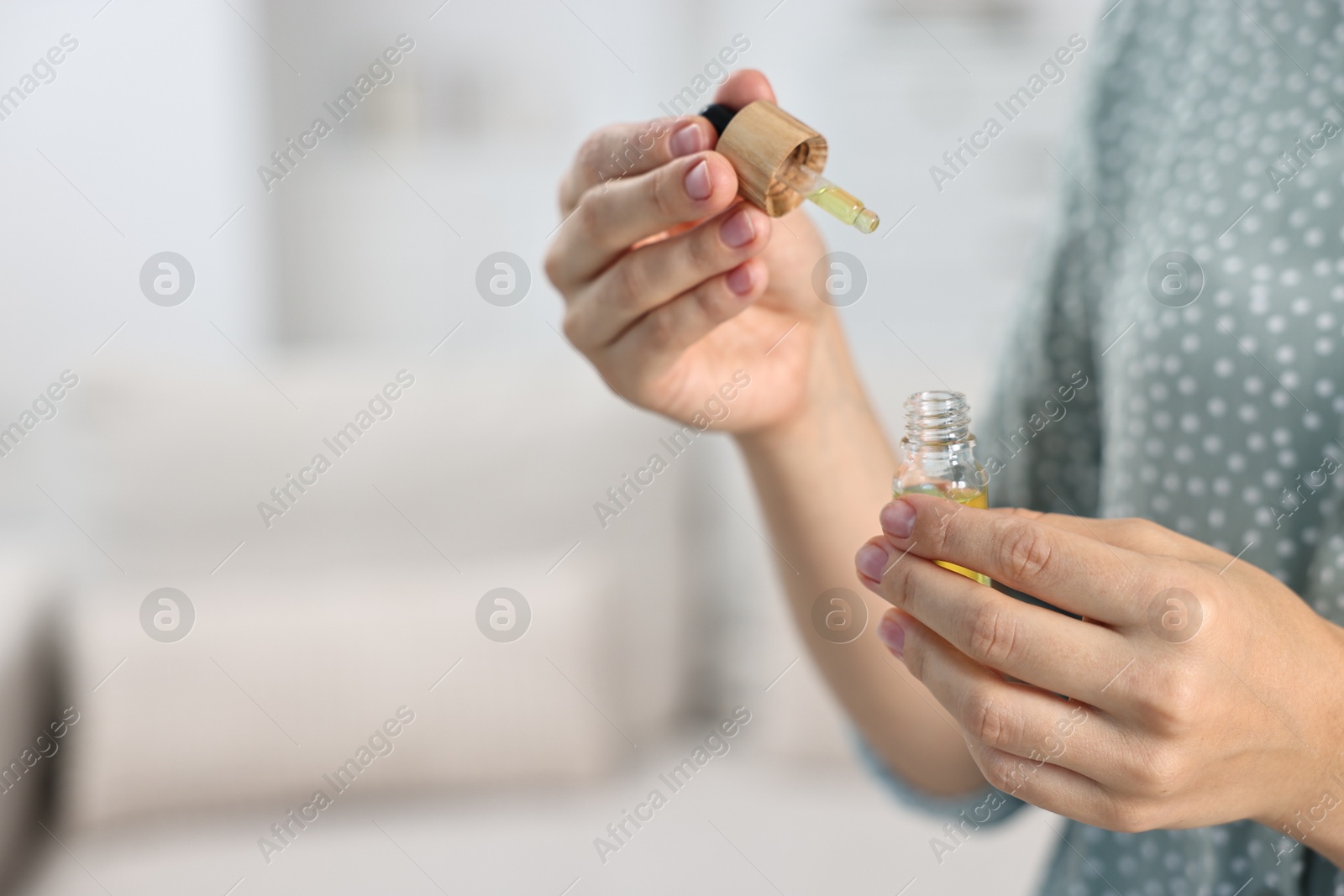 Photo of Young woman taking CBD tincture indoors, closeup. Space for text