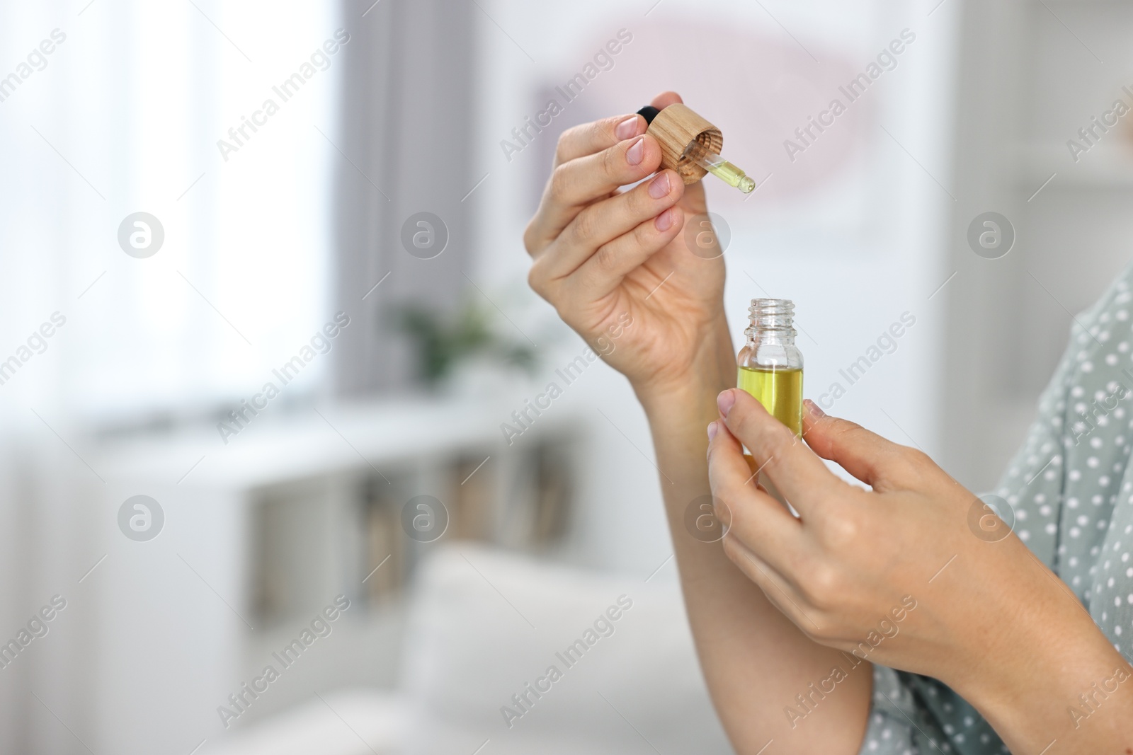 Photo of Young woman taking CBD tincture indoors, closeup. Space for text