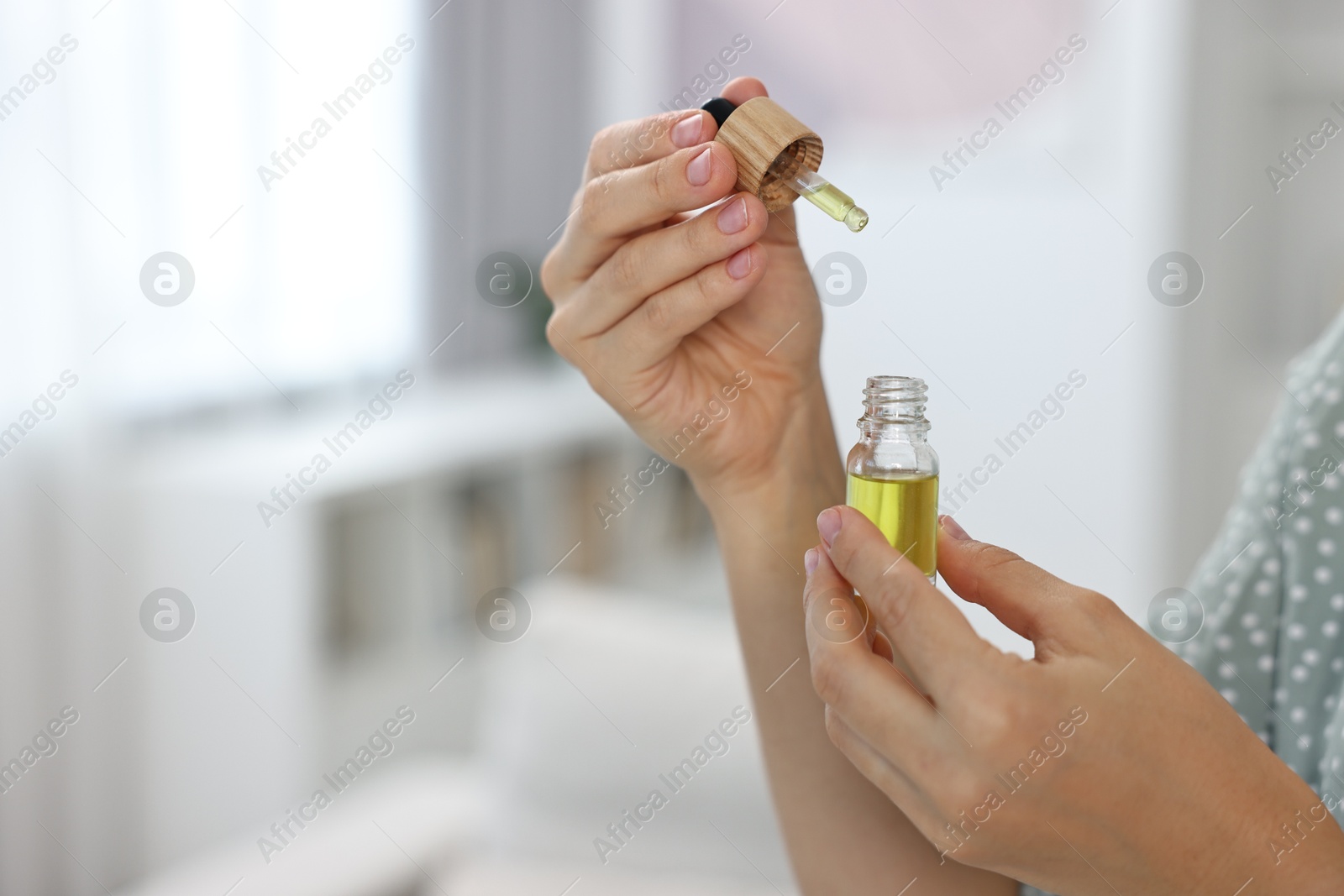 Photo of Young woman taking CBD tincture indoors, closeup. Space for text