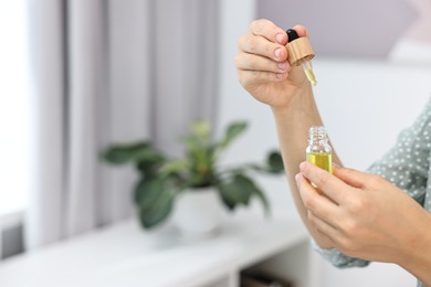 Young woman taking CBD tincture indoors, closeup. Space for text