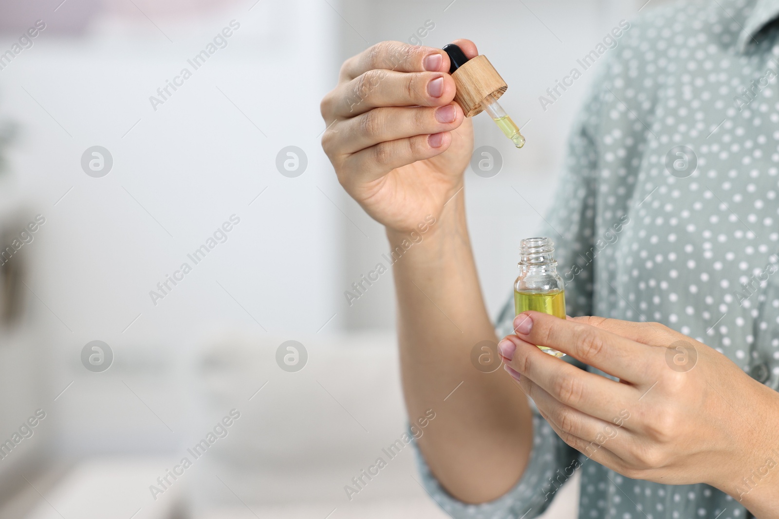 Photo of Young woman taking CBD tincture indoors, closeup. Space for text