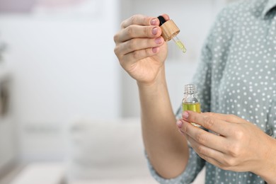 Photo of Young woman taking CBD tincture indoors, closeup. Space for text